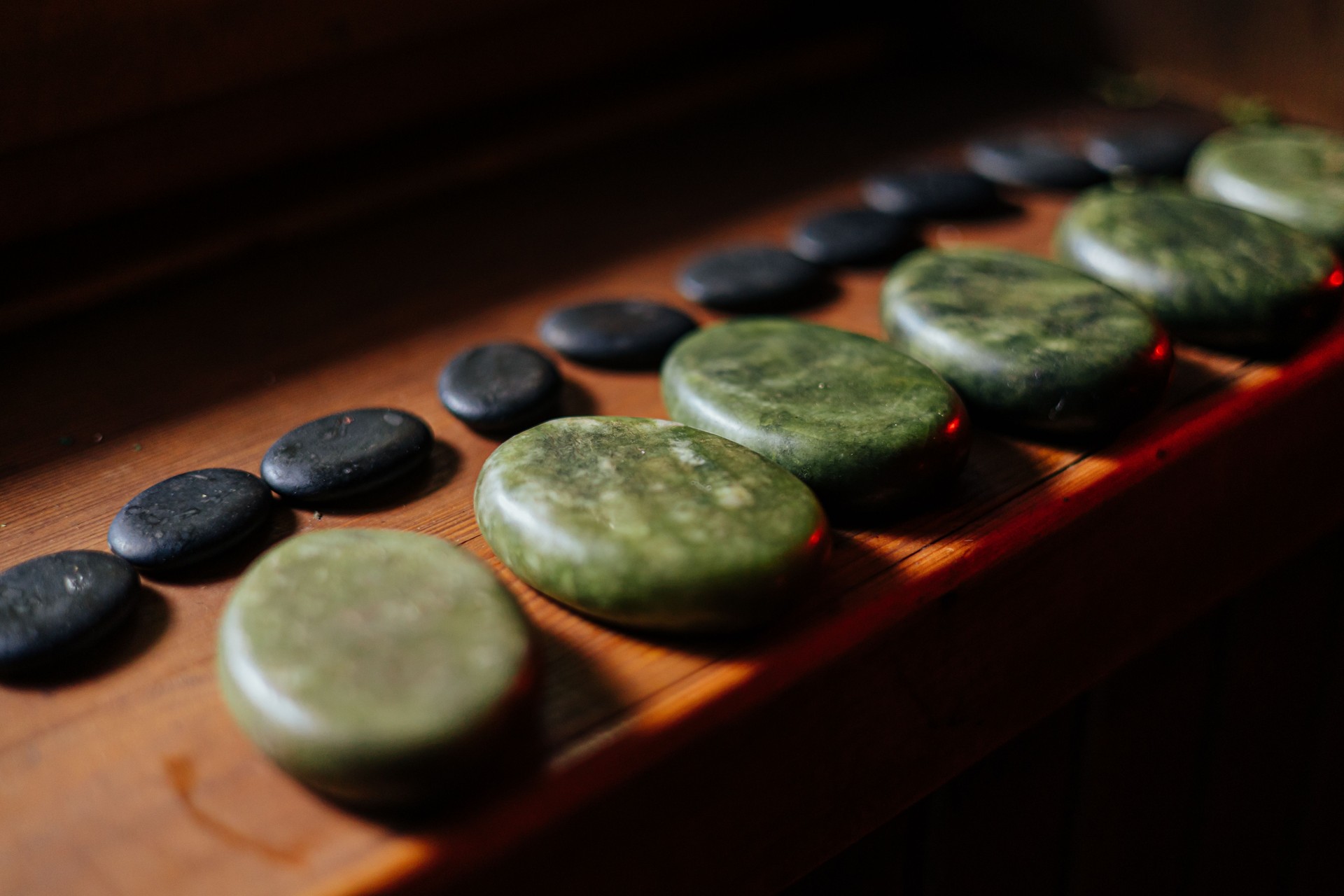 Polished Jade and Basalt Massage Stones on Wooden Bench